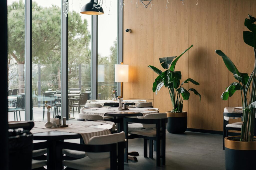 Elegant restaurant interior with modern decor in Istanbul, featuring large windows and lush greenery.